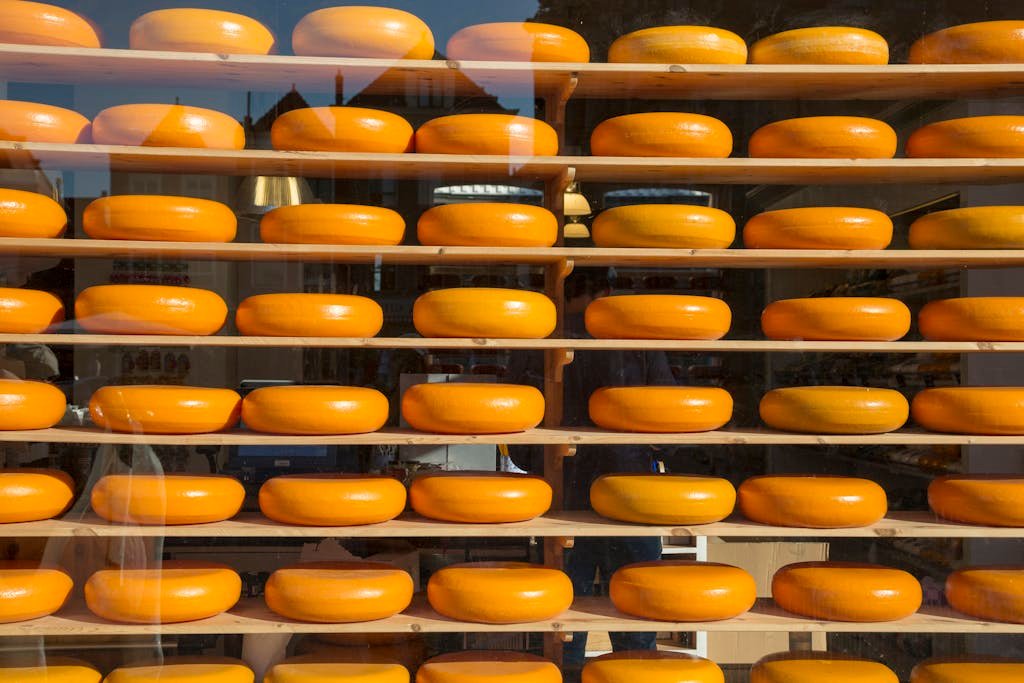 Brightly colored cheese wheels arranged on shelves behind a glass window, creating a vibrant display.